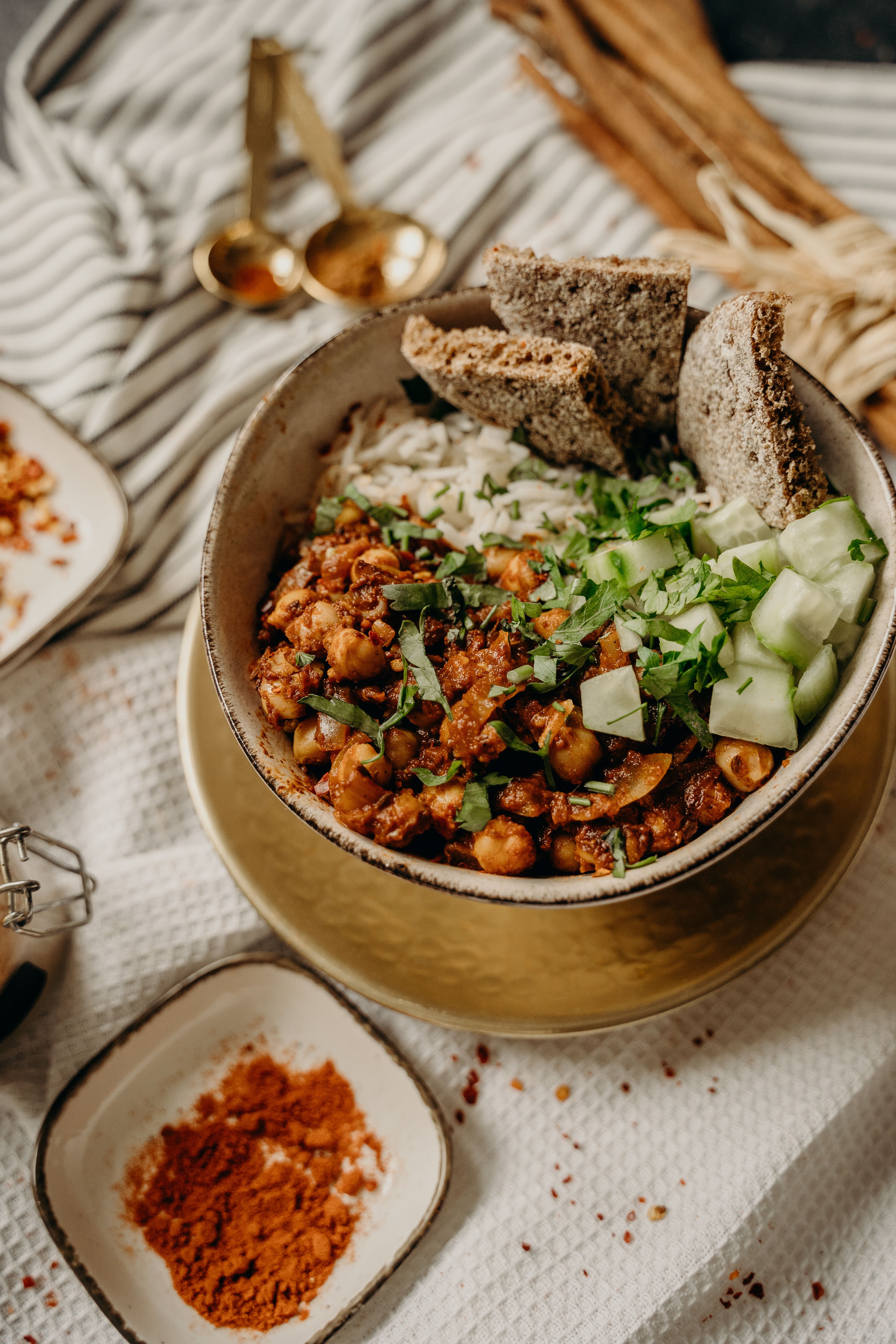 A bowl of freshly cooked kitchari surrounded by Ayurvedic herbs and turmeric root on a stone surface